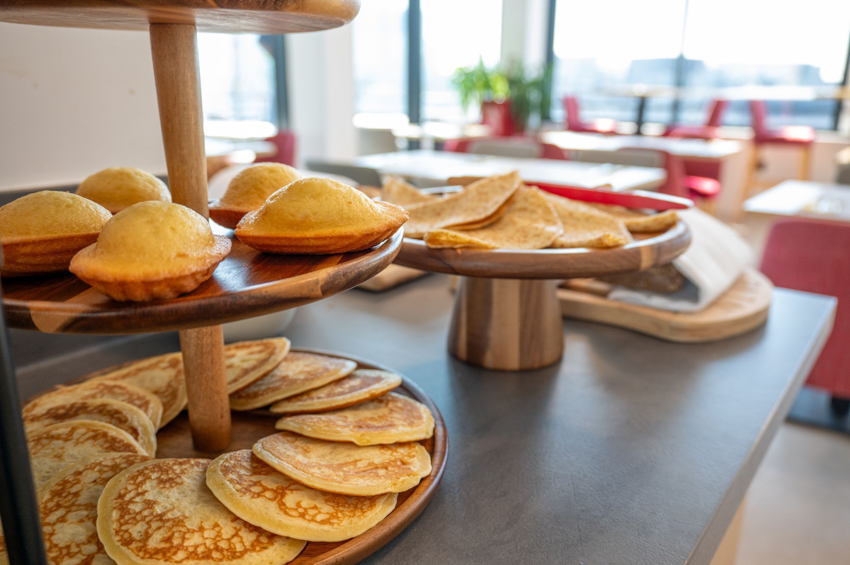 A breakfast buffet with various pastries and pancakes on wooden serving boards.
