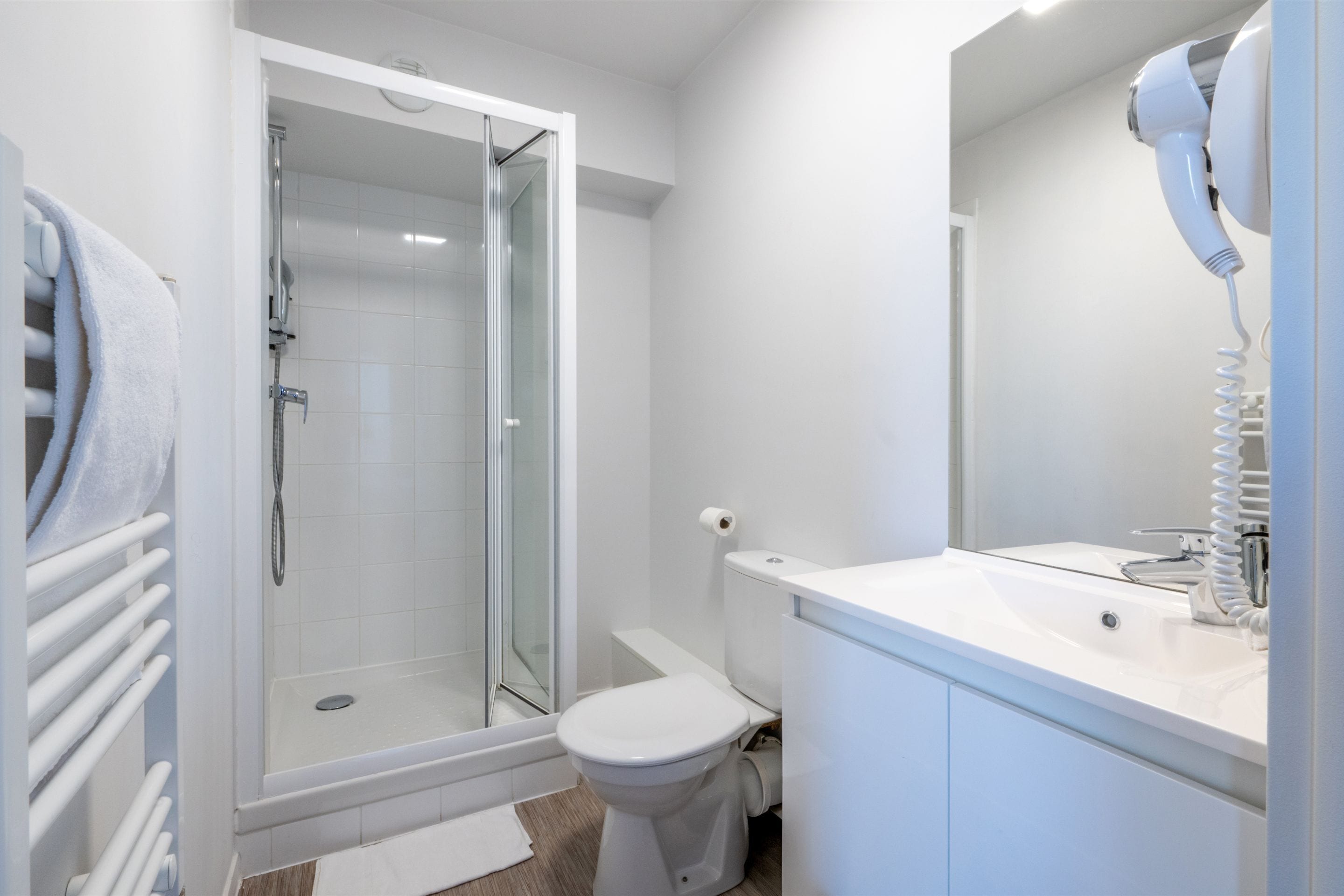 Une salle de bain moderne avec une douche à parois de verre, des toilettes blanches et un lavabo avec un miroir.