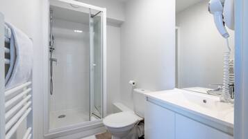 Une salle de bain moderne avec une douche à parois de verre, des toilettes blanches et un lavabo avec un miroir.