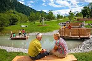 Eine Flusslandschaft mit einer Holzbrücke, Picknicktischen und einer natürlichen Umgebung.