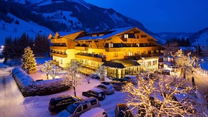 Ein mehrstöckiges Hotel mit Restaurant und Café, umgeben von schneebedeckten Bäumen und Bergen.