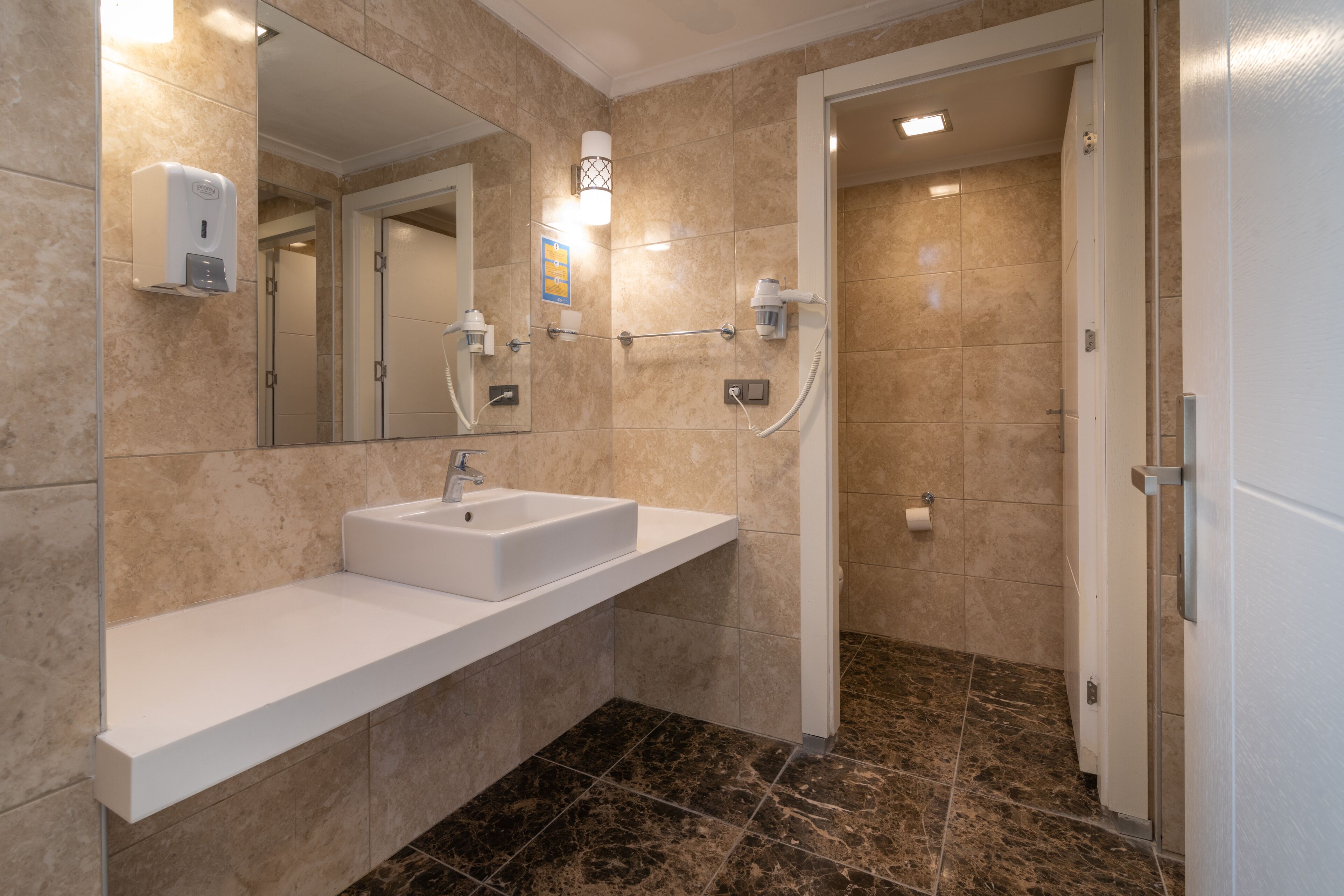 A modern bathroom with a white sink, a mirror, a handheld showerhead, and a towel rack.