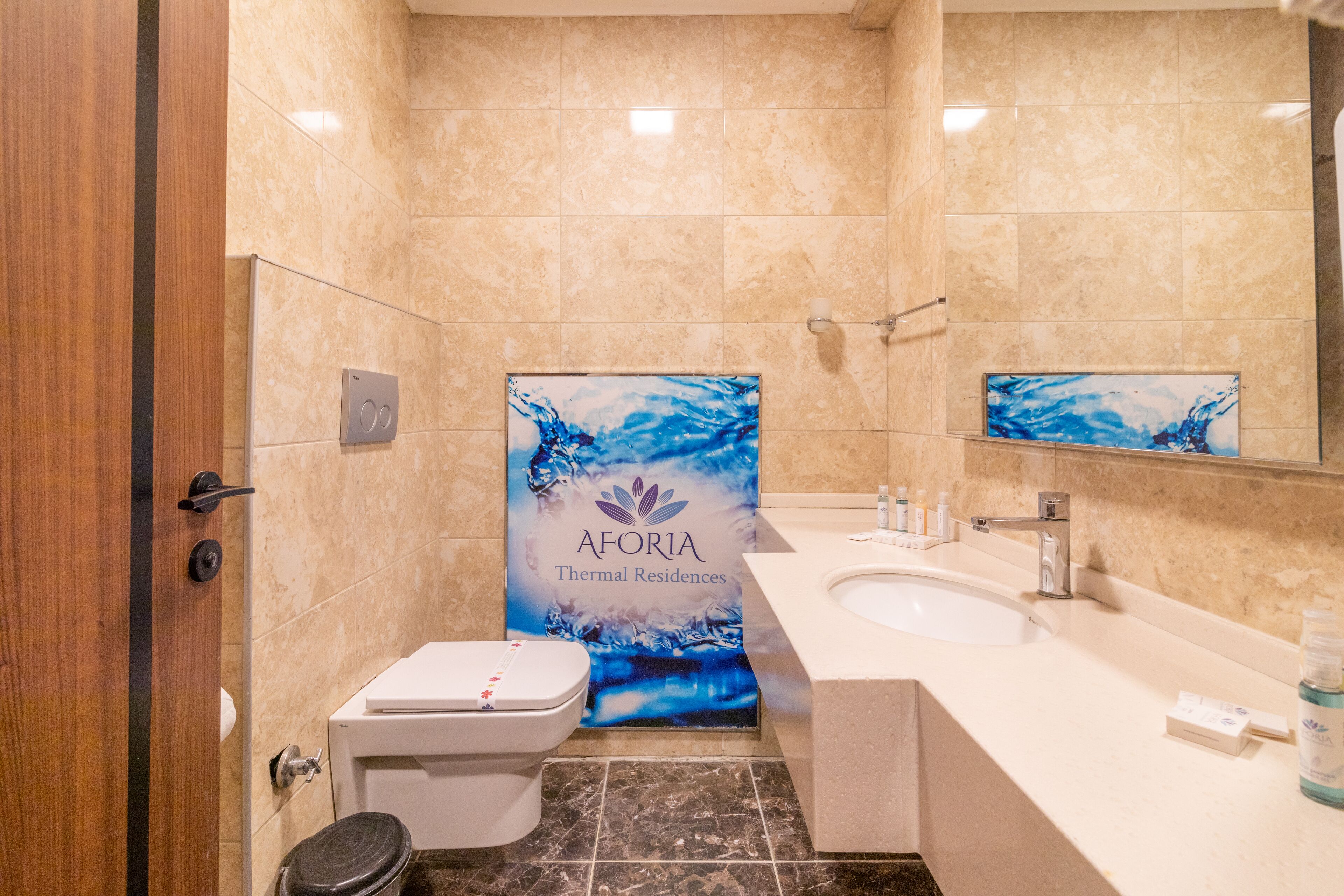 Un baño con inodoro, lavamanos y cortina de ducha con diseño abstracto azul.