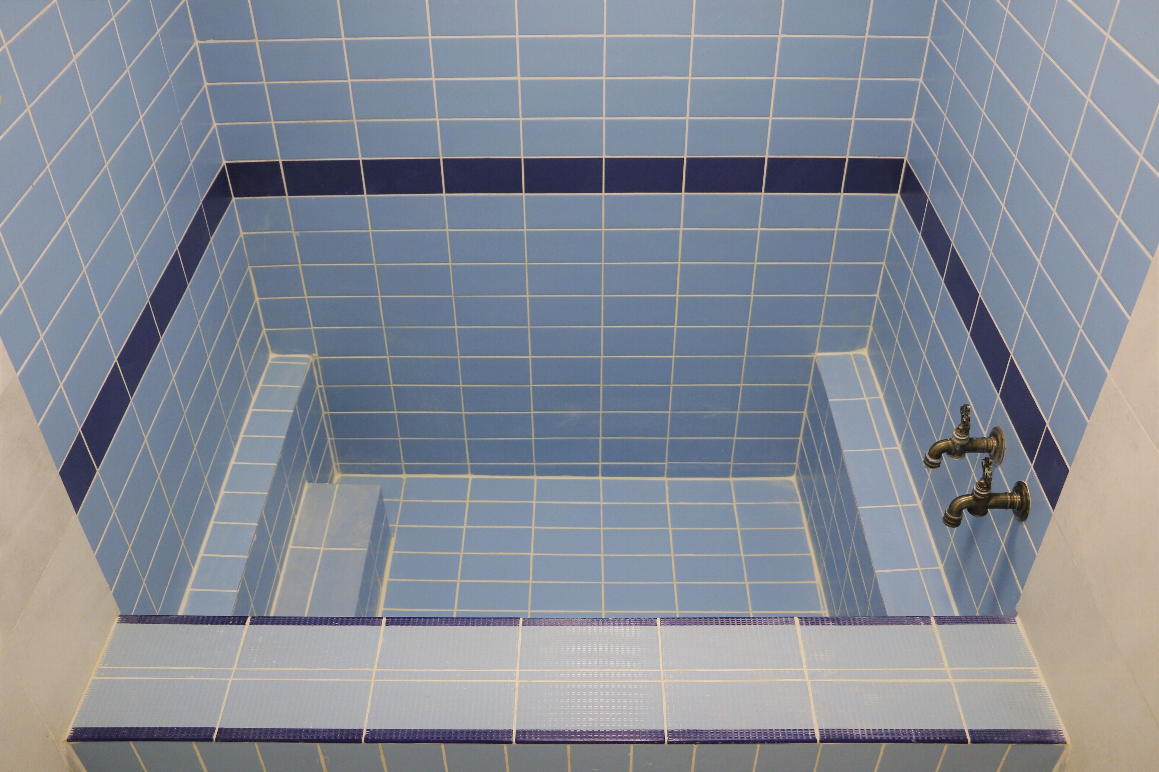 A bathroom with blue tiled walls and a visible shower area.