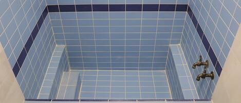 A bathroom with blue tiled walls and a visible shower area.