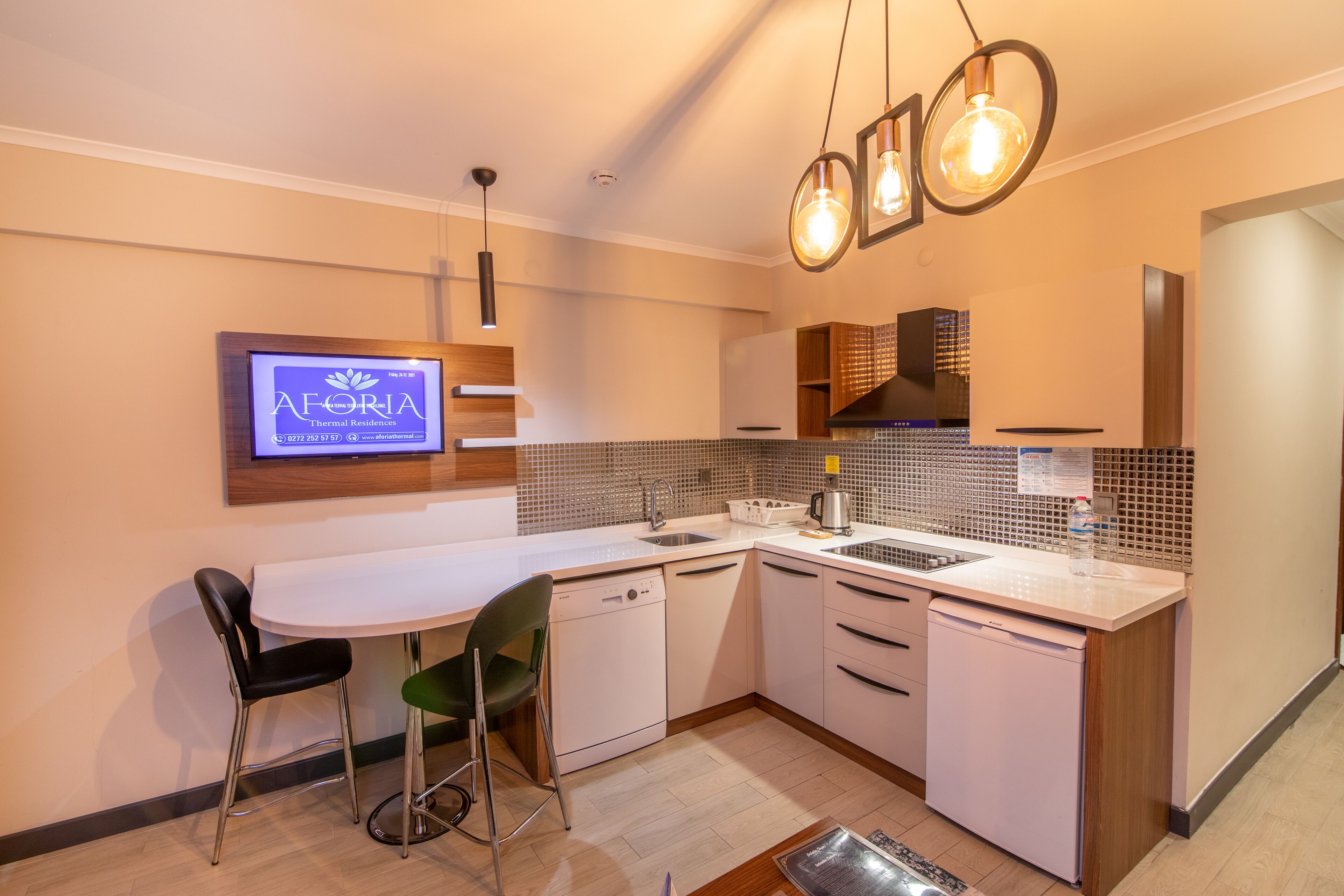 Una cocina moderna con lavavajillas integrado, un fregadero y una zona de comedor con dos sillas.