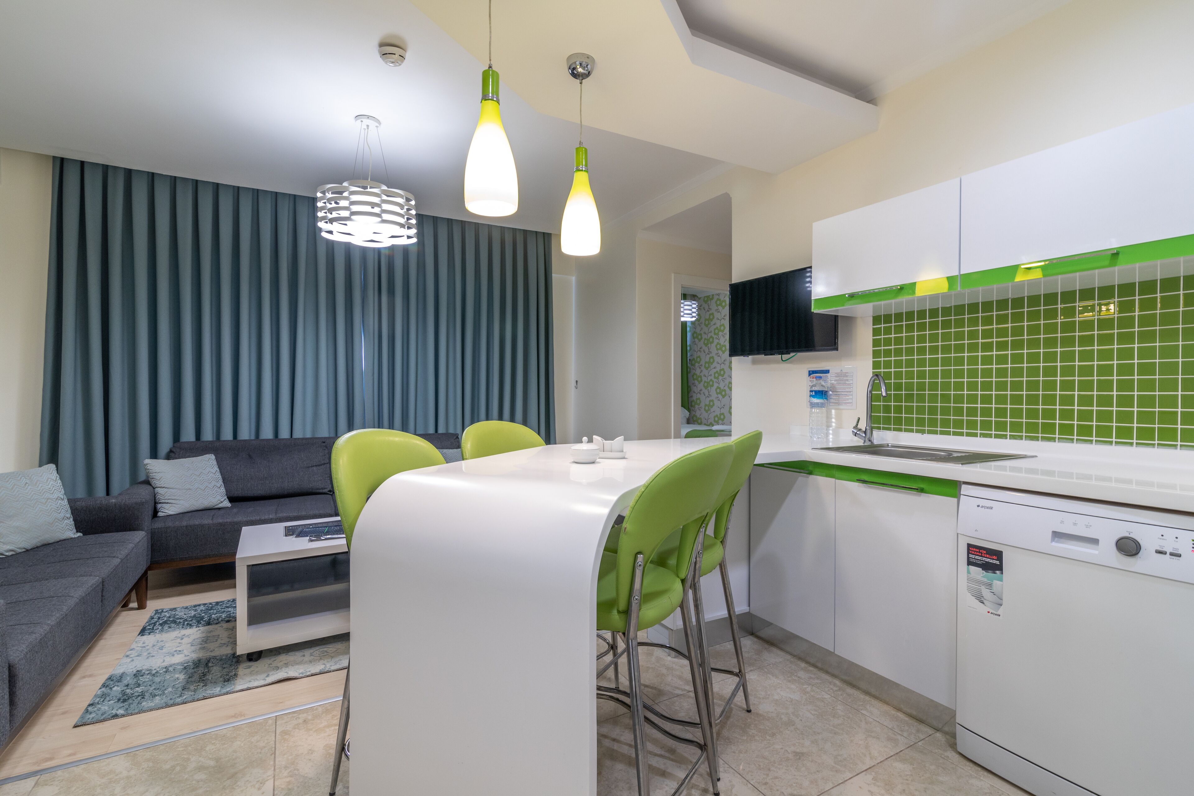 Een moderne keuken met witte kastjes, een groene spatwand en een inbouwvaatwasser.