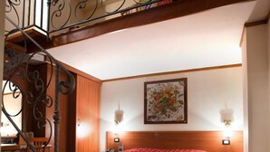 A bedroom with a bed, a desk, and a staircase with a decorative railing. - Hermitage Capua Hotel (Vitulazio)