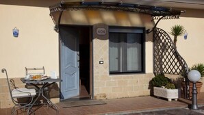 A building with a door marked '404', a small table with chairs, and a metal fence with plants. - Hermitage Capua Hotel (Vitulazio)