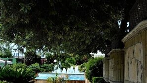 A paved pathway leading to a building with classical architecture, surrounded by lush greenery and a small fountain. - Hermitage Capua Hotel (Vitulazio)