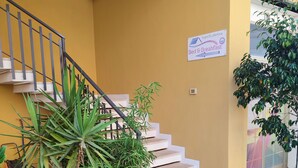 Una escalera con una pared amarilla, plantas en macetas y un letrero que indica un área de desayuno.