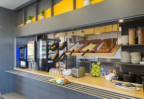 Una barra de desayuno con diversos alimentos, una máquina de café y un tostador.