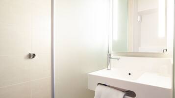 Une salle de bain avec un lavabo blanc, un miroir et une serviette suspendue à un porte-serviettes.