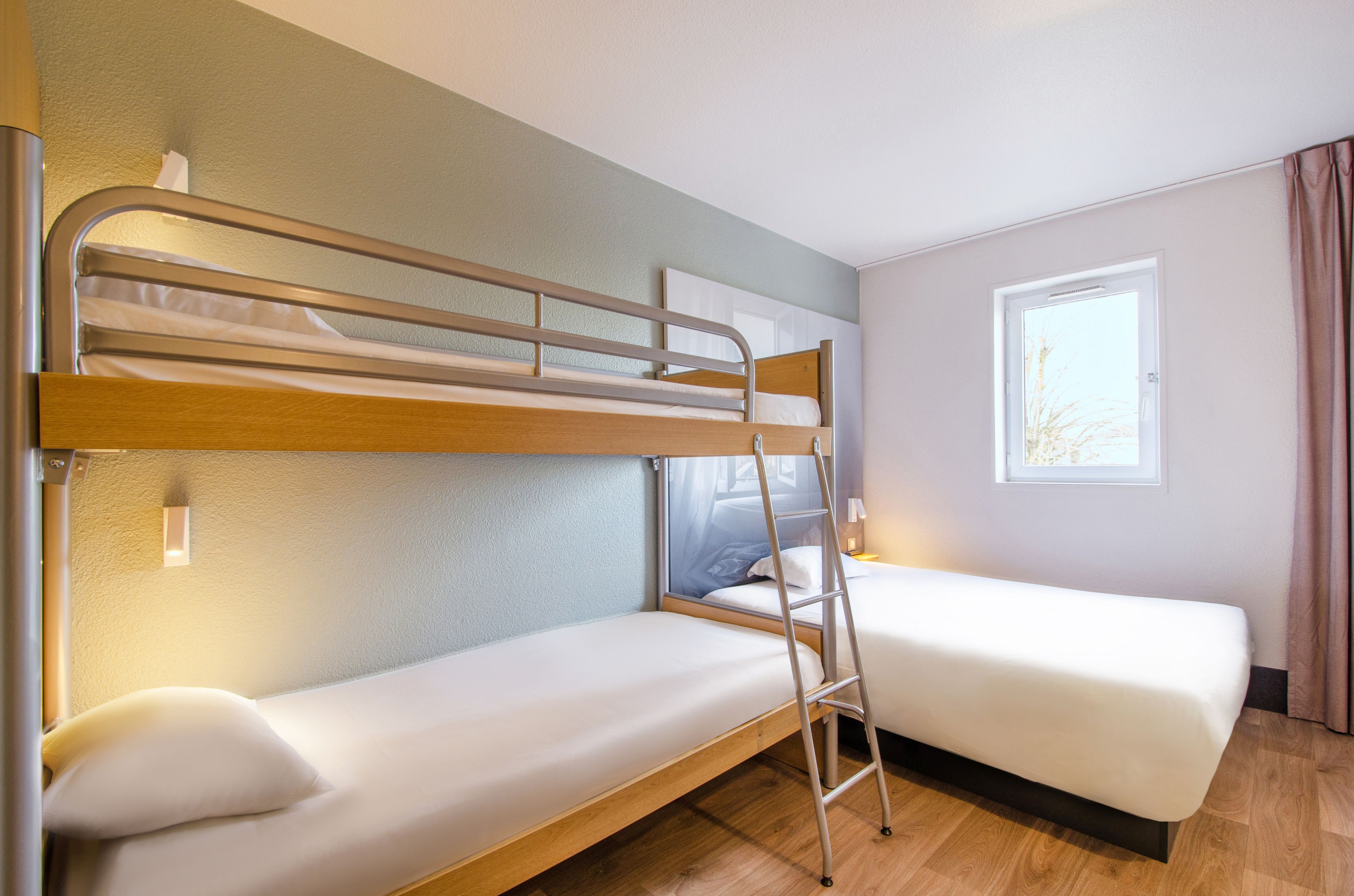 Habitación con literas, una escalera, ventana y mesita de noche.