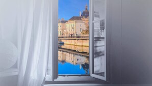 An open window with a view of a building and a reflection in the water.