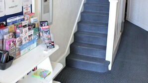 A staircase with a carpeted floor and white railings, leading to an upper level.
