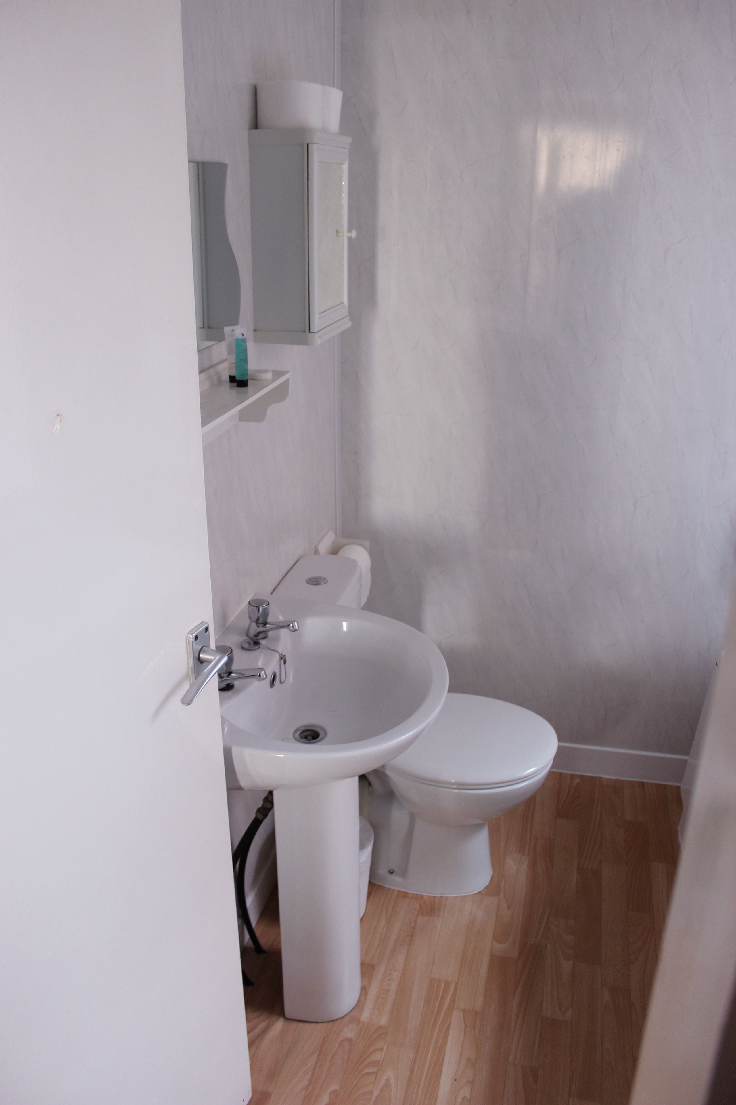 A small bathroom with a white sink, toilet, and cabinet.