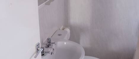 A small bathroom with a white sink, toilet, and cabinet.