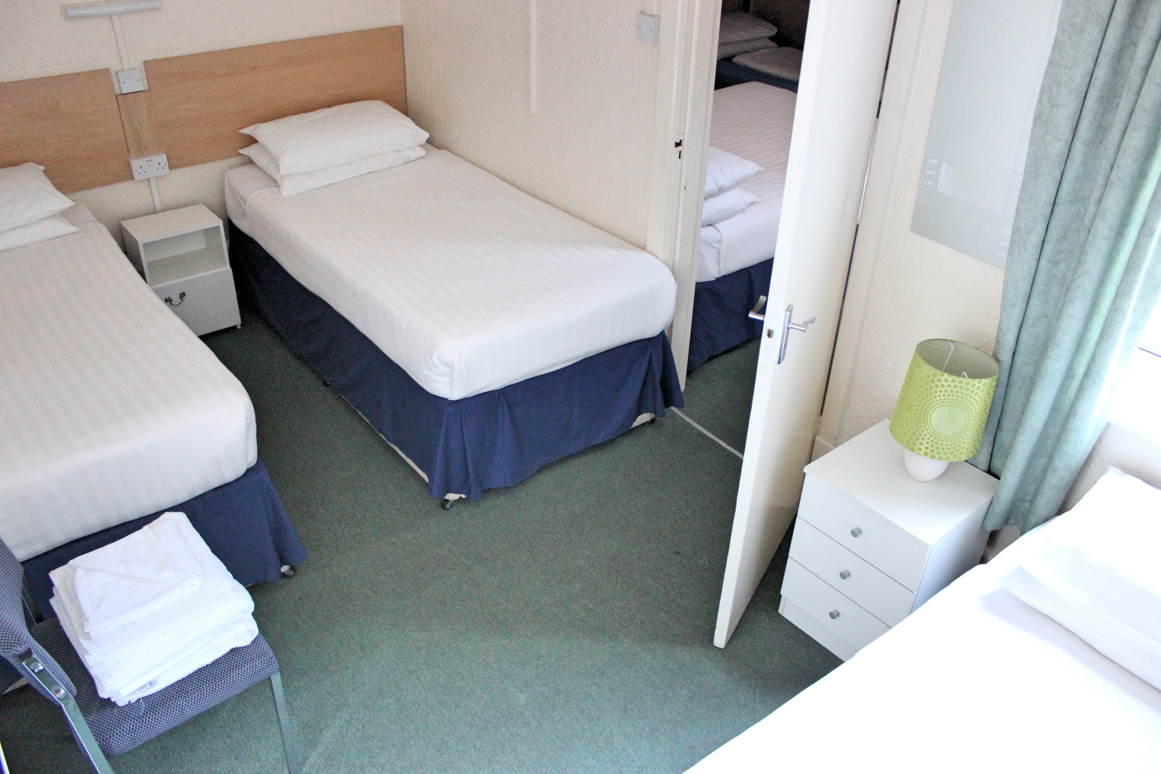 A hotel room with two beds, a small bedside table, a nightstand, and a mirror.