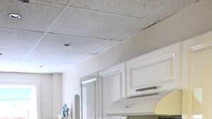 A kitchen with white cabinets, a stove, and a window with blinds.