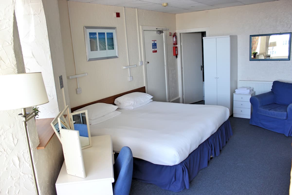 Une chambre d’hôtel comprenant un lit, un bureau, une chaise, une armoire et un miroir.