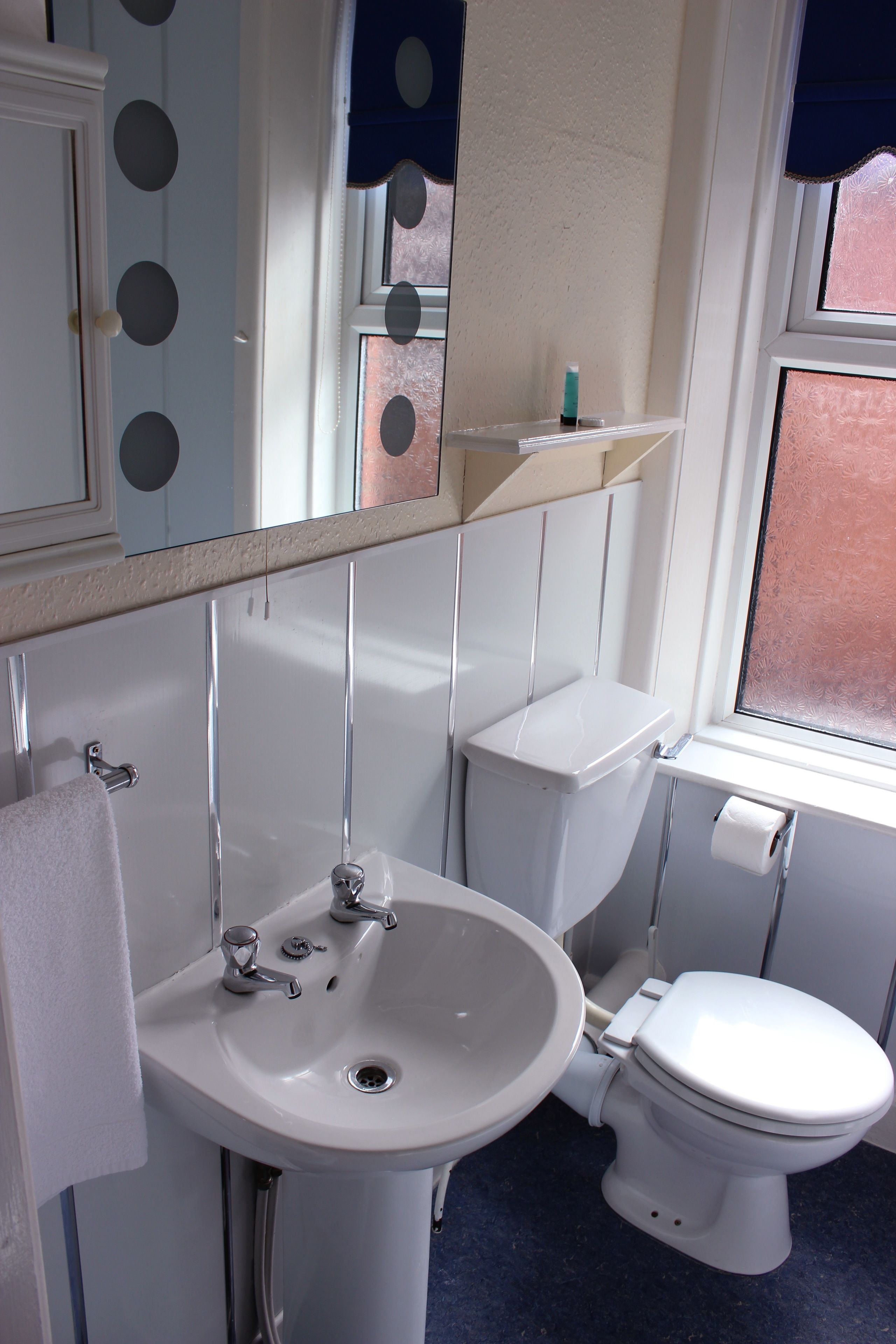Ein Badezimmer mit einem weißen Waschbecken, einer Toilette und einem Spiegel über dem Waschbecken.