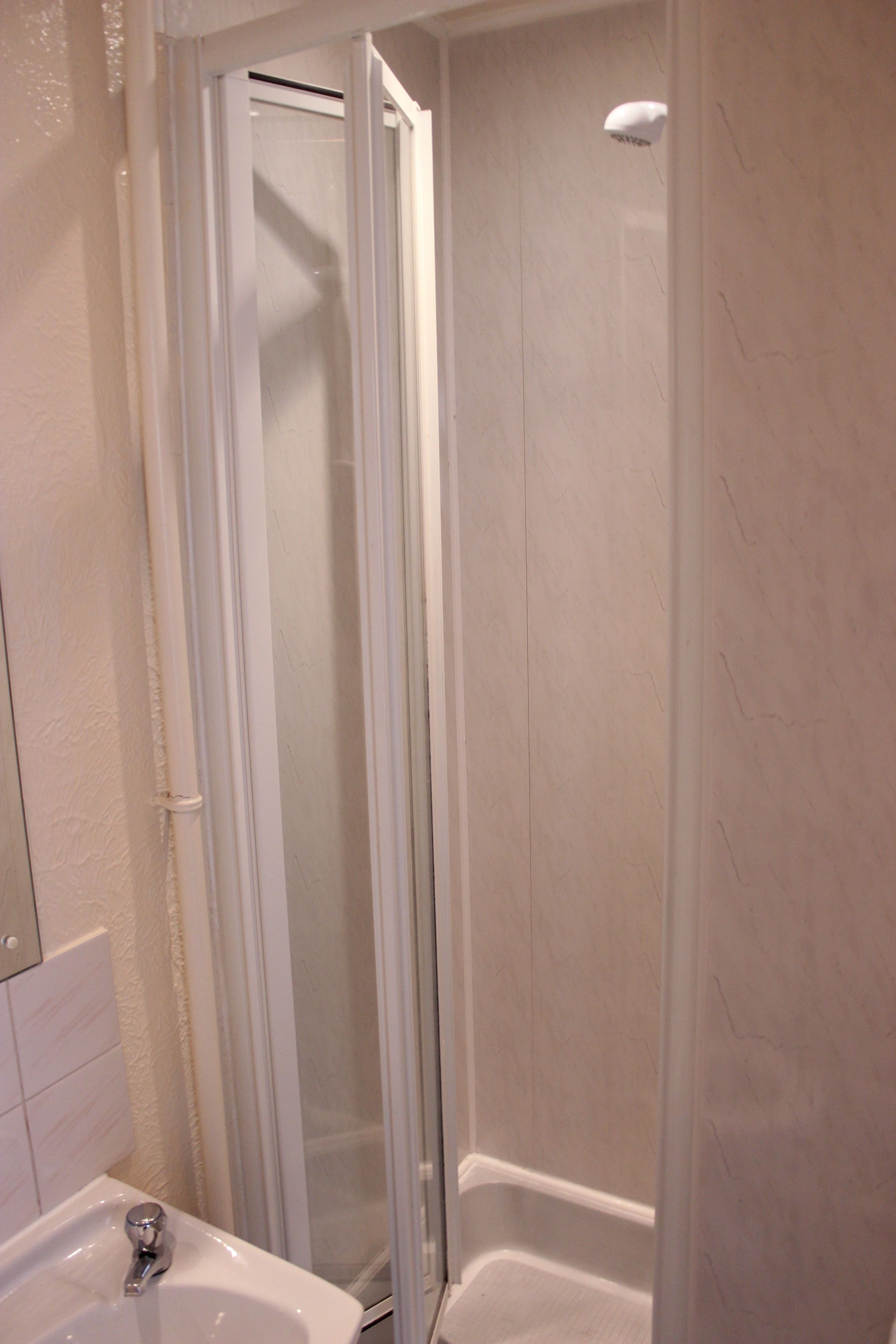 Un baño con cabina de ducha de vidrio, un lavabo blanco y un espejo.