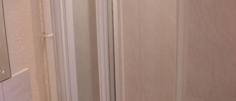 Un baño con cabina de ducha de vidrio, un lavabo blanco y un espejo.