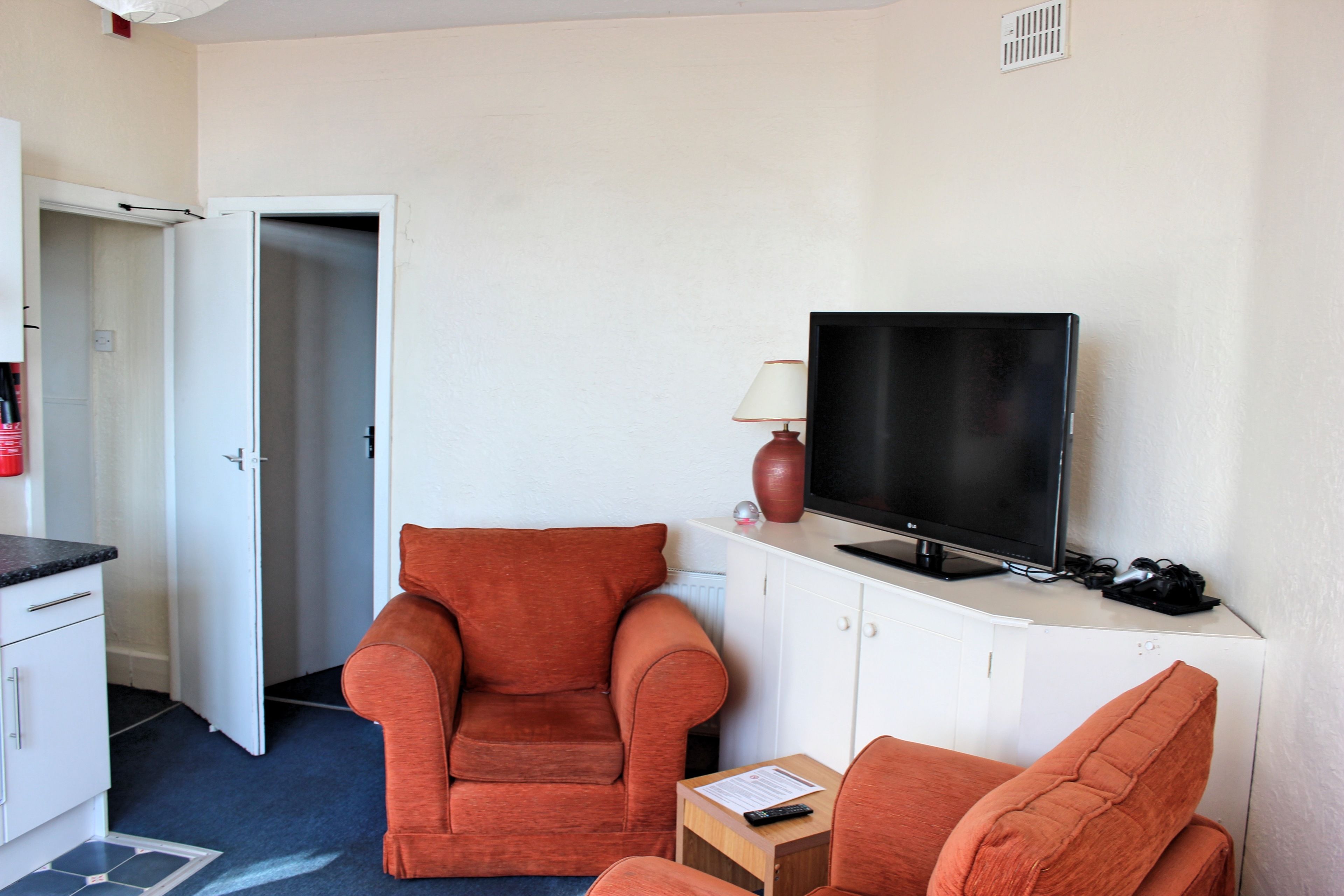 A hotel room with a sofa, a TV, a lamp, and a cabinet.