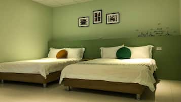 Dos camas individuales con ropa blanca y almohadas de colores diferentes en una habitación con paredes verdes y piso de baldosas.