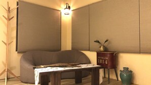 A room with a sofa, a small table, a decorative vase, and a wall-mounted light fixture.