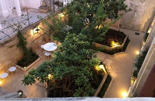 Un patio al aire libre con suelo de piedra, plantas en macetas y mobiliario exterior.