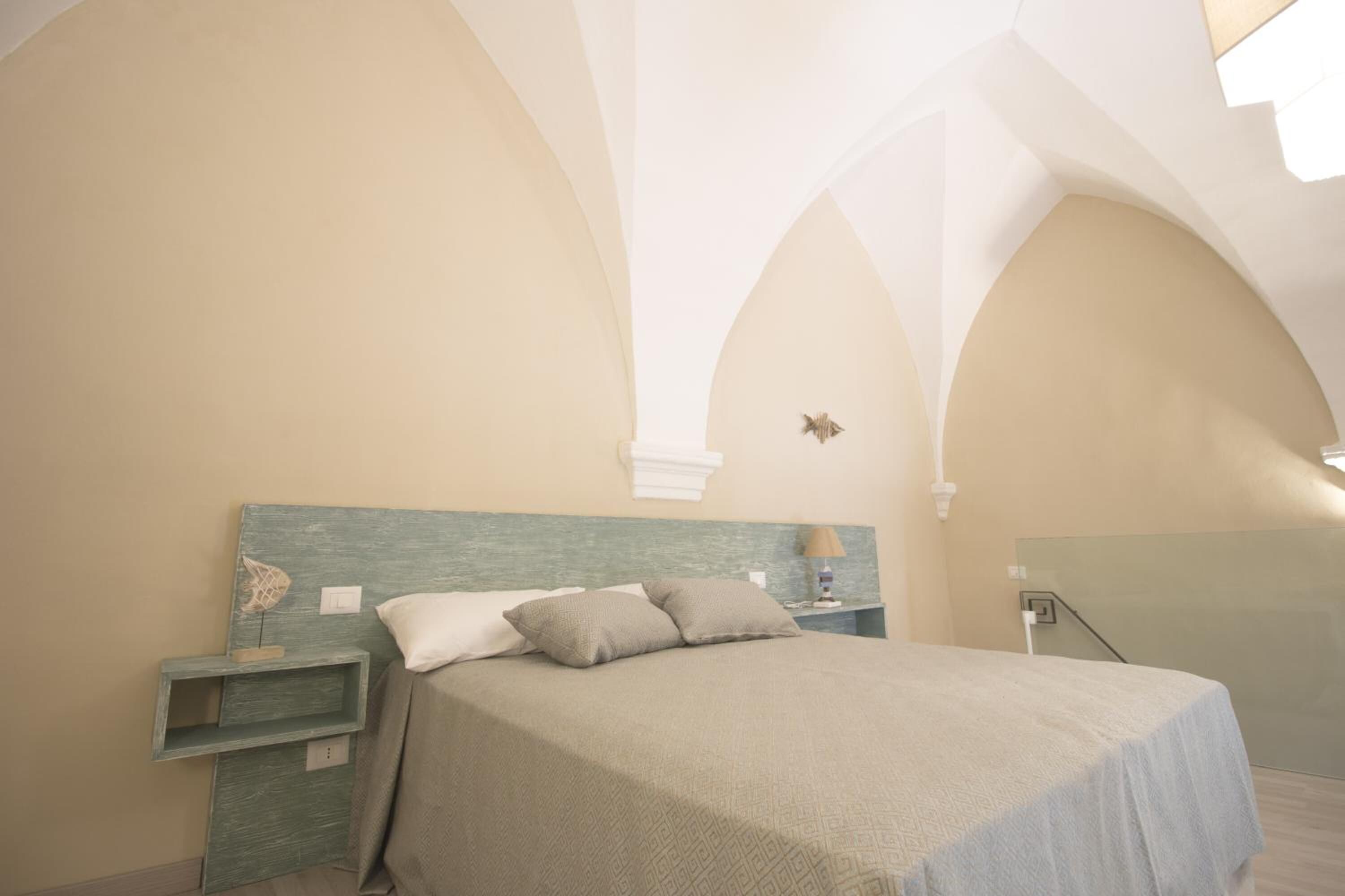 Un dormitorio con cama, mesitas de noche y espejo.