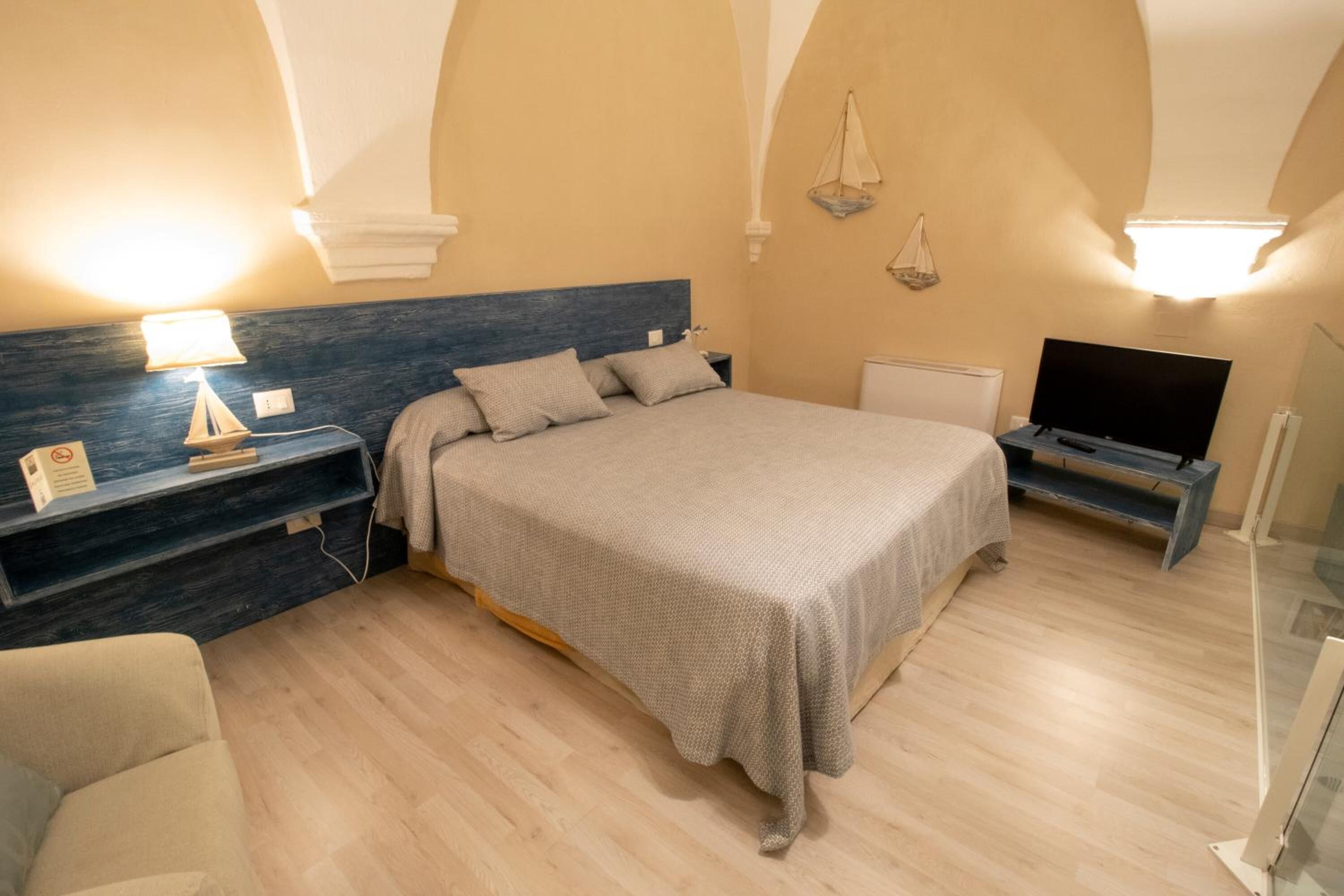 Une chambre à coucher avec un lit, des tables de chevet, une télévision et une chaise.