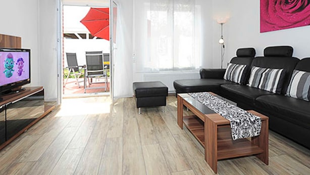 A modern living room with a black sofa, a wooden coffee table, and a television on a stand.