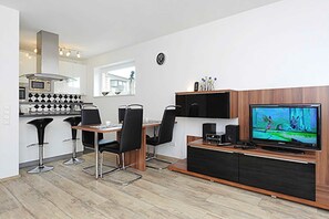 A modern kitchen with a dining area, a TV, and a coffee machine.