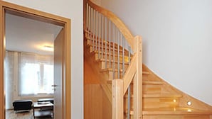 A wooden staircase with a curved design leading to a landing.