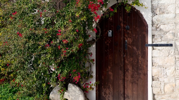 A stone wall with a wooden door and a large rock. - Old Olive Mill House by TrulyCyprus (Dhoros)