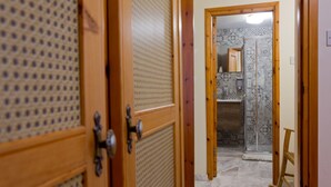 A hallway with wooden doors, a tiled shower area, and a small wooden stool. - Old Olive Mill House by TrulyCyprus (Dhoros)