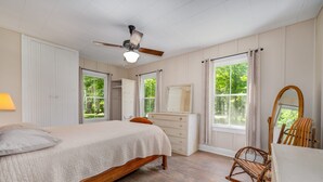 Un dormitorio con cama, cómoda, mecedora y ventilador de techo.
