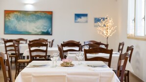 Un espace repas avec des tables dressées pour le repas, des chaises en bois et un luminaire décoratif.