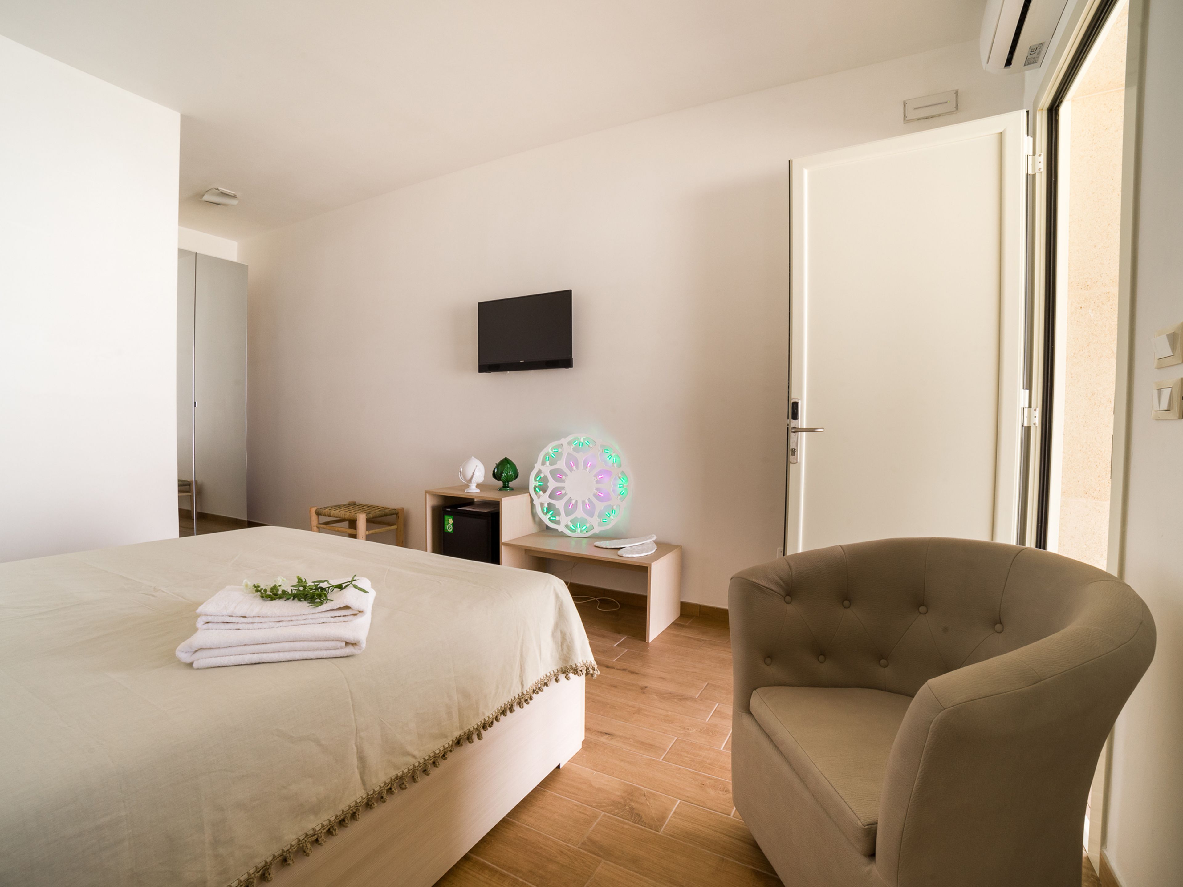 Una habitación de hotel con una cama, una silla, un escritorio, un televisor y una puerta.