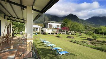 Relax in a serene garden setting with a patio area and outdoor seating, overlooking the lush mountains.