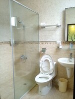 Baño con ducha de mampara de vidrio, inodoro y lavamanos.