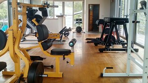 A gym with various exercise equipment, large windows, and a wooden floor. - Moonrise Inn (Donghe)