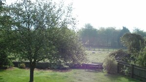 A grassy outdoor area with a tree, a bench, and a fence. - Well Cottage B&B (Cirencester)