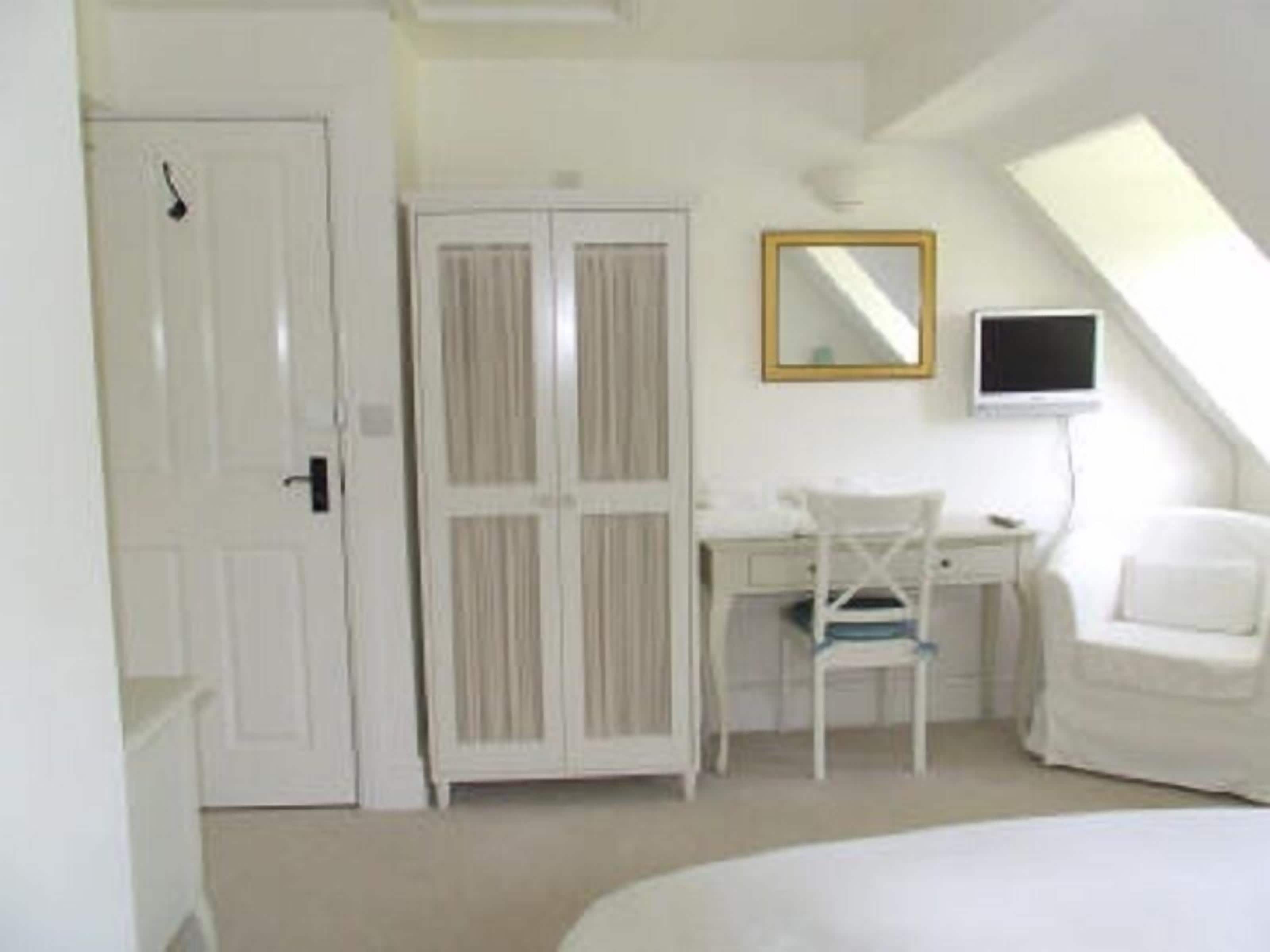 A bedroom with a bed, a desk, a chair, and a wardrobe.