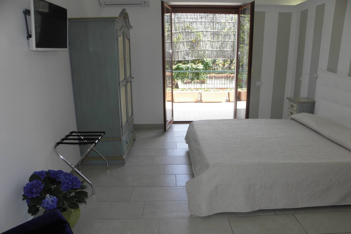 A bedroom with a bed, a wardrobe, a chair, and a potted plant.