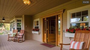 Een overdekte veranda met houten stoelen en een houten deur.
