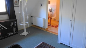 A room with a radiator, a white wardrobe, a bookshelf, and a window with curtains. - Haus Fermate (Wilhelmsfeld)